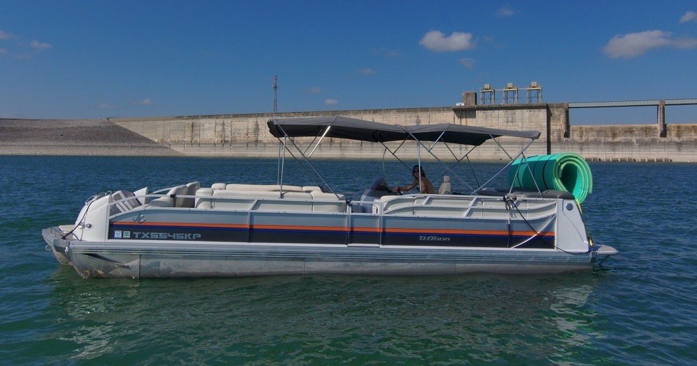 Grey boat rental gliding over Lake Travis water